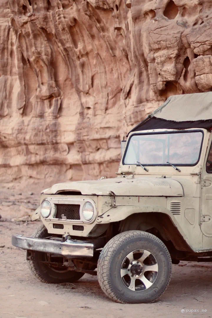 Un vecchio fuoristrada Toyota color sabbia davanti a una parete di arenaria