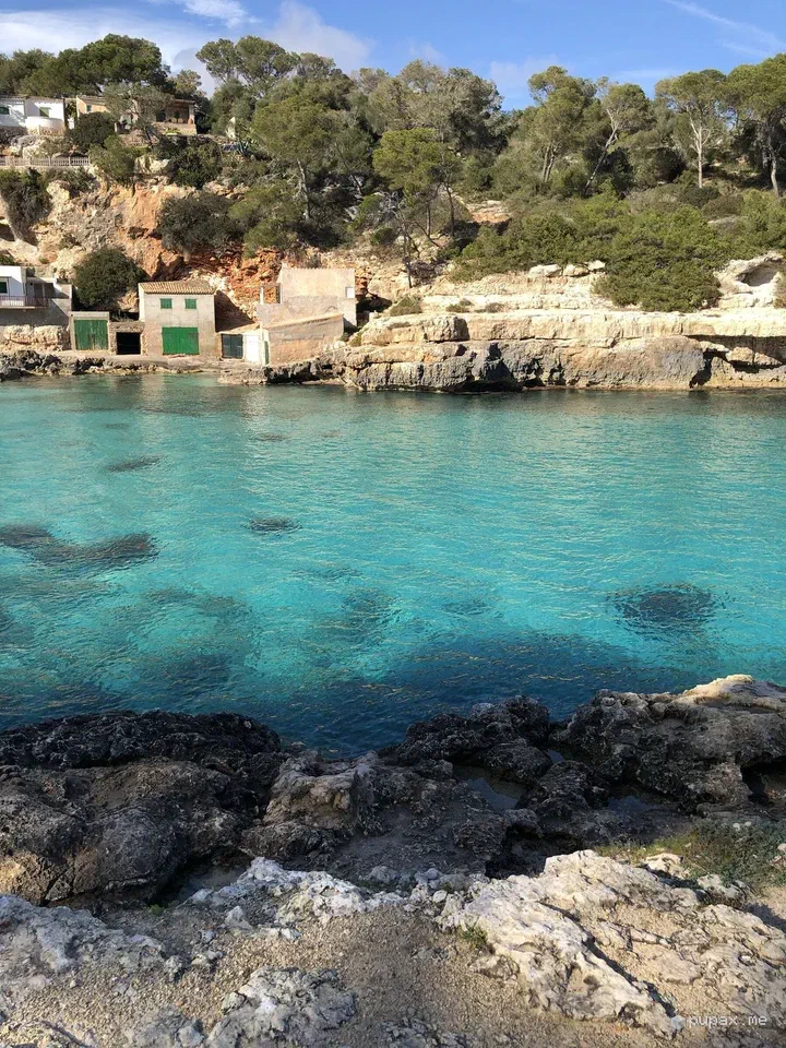 La caletta di Cala Llombards con l'acqua turchese e le rimesse per le barche