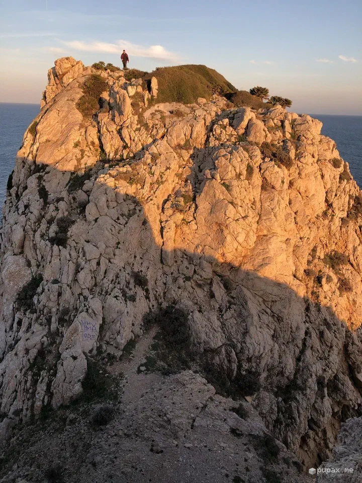 Una scogliera di Capdepera illuminata d'arancio dal sole al tramonto