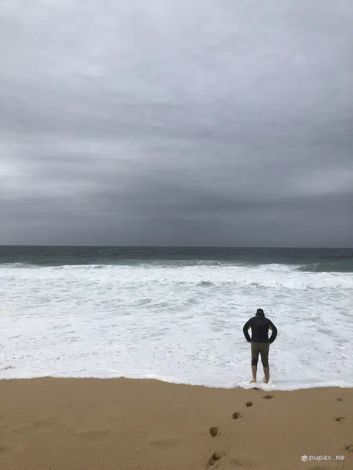La spiaggia di Comporta sotto il cielo grigio, con una persona di spalle davanti alle onde