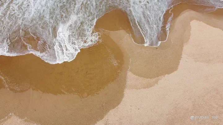 Vista dal drone della schiuma delle onde sulla sabbia dorata di Praia do Amado