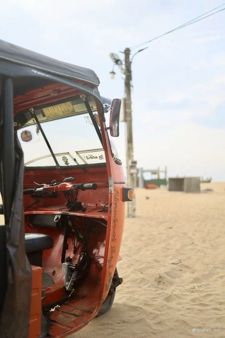 Un tuk-tuk rosso parcheggiato sulla sabbia della spiaggia di Negombo