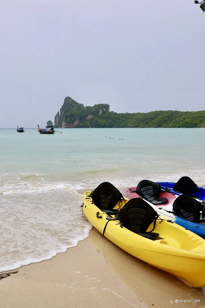 Kayak gialli allineati sulla spiaggia di Phi Phi, con il cielo grigio di pioggia